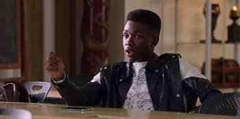 Movie still from “Secret Society of Second Born Royals” (2020), directed by Anna Mastro – A man sitting at a table with a cell phone in front of him; Close Up shot, Over the shoulder angle