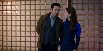 Movie still from “Secret Society of Second Born Royals” (2020), directed by Anna Mastro – A man and a woman standing next to each other in front of a brick wall; Medium shot, Over the shoulder angle