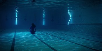 Movie still from “Secret Society of Second Born Royals” (2020), directed by Anna Mastro – A woman sitting in a swimming pool under water; Extreme Wide shot, High angle