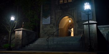 Movie still from “Secret Society of Second Born Royals” (2020), directed by Anna Mastro – A person walking down the steps of a building at night; Extreme Wide shot, High angle