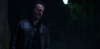 Movie still from “Secret Society of Second Born Royals” (2020), directed by Anna Mastro – A man wearing a leather jacket standing in the dark; Medium shot, Low angle