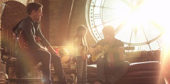 Movie still from “Secret Society of Second Born Royals” (2020), directed by Anna Mastro – A group of people sitting in front of a clock; Medium shot, Low angle
