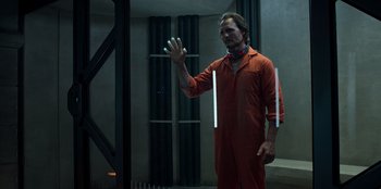 Movie still from “Secret Society of Second Born Royals” (2020), directed by Anna Mastro – A man in an orange jumpsuit holding a white object; Medium shot, Low angle