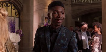 Movie still from “Secret Society of Second Born Royals” (2020), directed by Anna Mastro – A young man in a suit smiling for the camera; Close Up shot, Over the shoulder angle
