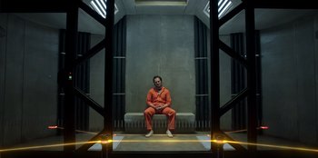 Movie still from “Secret Society of Second Born Royals” (2020), directed by Anna Mastro – A man in a orange suit sitting on a bench; Wide shot, Low angle