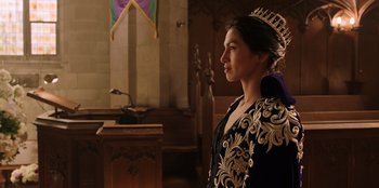Movie still from “Secret Society of Second Born Royals” (2020), directed by Anna Mastro – A woman wearing a crown standing next to a table; Close Up shot, Over the shoulder angle