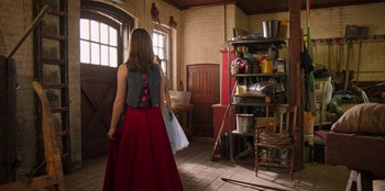 Movie still from “Secret Society of Second Born Royals” (2020), directed by Anna Mastro – A woman standing in front of a shelf in a room; Wide shot, Over the shoulder angle