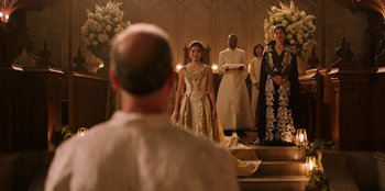 Movie still from “Secret Society of Second Born Royals” (2020), directed by Anna Mastro – A group of people standing in front of a stage; Wide shot, Over the shoulder angle