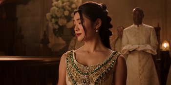 Movie still from “Secret Society of Second Born Royals” (2020), directed by Anna Mastro – A woman in a gold and green dress; Close Up shot, Over the shoulder angle