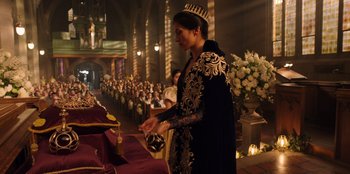 Movie still from “Secret Society of Second Born Royals” (2020), directed by Anna Mastro – A woman wearing a crown standing in front of a group of people; Medium shot, Over the shoulder angle