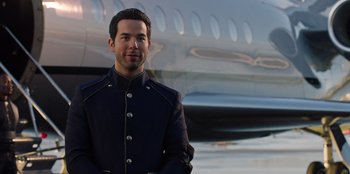 Movie still from “Secret Society of Second Born Royals” (2020), directed by Anna Mastro – A man standing in front of an airplane; Medium shot, Low angle