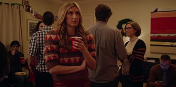 Movie still from “See You Next Christmas” (2021), directed by Christine Weatherup – A woman holding a cup of coffee in a room; Medium shot, Over the shoulder angle