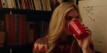 Movie still from “See You Next Christmas” (2021), directed by Christine Weatherup – A woman drinking from a red cup in a room; Close Up shot, Over the shoulder angle