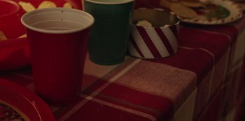 Movie still from “See You Next Christmas” (2021), directed by Christine Weatherup – A table topped with cups and a bowl of food; Extreme Close Up shot, High angle