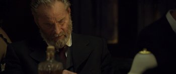 Movie still from “Blackthorn” (2011), directed by Mateo Gil – An older man in a suit and a red neck tie; Close Up shot, Over the shoulder angle