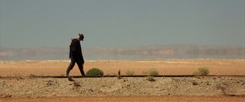 Movie still from “Blackthorn” (2011), directed by Mateo Gil – A man walking on a dirt road next to a field; Extreme Wide shot, Low angle