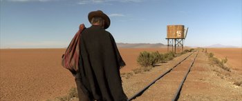 Movie still from “Blackthorn” (2011), directed by Mateo Gil – An older man in a cowboy hat and poncho walking in the desert; Wide shot, Low angle