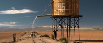 Movie still from “Blackthorn” (2011), directed by Mateo Gil – A man standing next to a water tower on the side of a road; Extreme Wide shot, Low angle