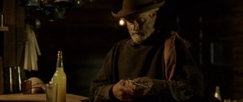 Movie still from “Blackthorn” (2011), directed by Mateo Gil – An older man in a hat is looking at his cell phone; Medium shot, High angle