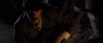 Movie still from “Blackthorn” (2011), directed by Mateo Gil – A man in a suit and a hat is sitting in the dark; Close Up shot, High angle