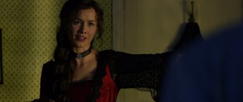 Movie still from “Blackthorn” (2011), directed by Mateo Gil – A woman in a red and black dress is posing for a picture; Close Up shot, Over the shoulder angle