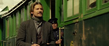Movie still from “Blackthorn” (2011), directed by Mateo Gil – A man standing next to another man on a train platform; Medium shot, Low angle