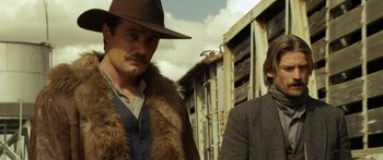 Movie still from “Blackthorn” (2011), directed by Mateo Gil – A man and a woman standing next to each other in front of a building; Medium shot, Low angle