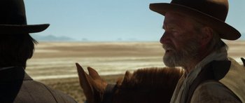Movie still from “Blackthorn” (2011), directed by Mateo Gil – An old man with a beard and a cowboy hat is looking at a horse; Close Up shot, Over the shoulder angle