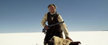 Movie still from “Blackthorn” (2011), directed by Mateo Gil – An older man holding a rifle over a dead animal; Medium shot, Low angle