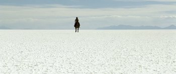 Movie still from “Blackthorn” (2011), directed by Mateo Gil – A man riding a horse across a snow covered field; Extreme Wide shot, Low angle