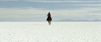 Movie still from “Blackthorn” (2011), directed by Mateo Gil – A man riding a horse across a snow covered field; Extreme Wide shot, Low angle