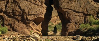 Movie still from “Blackthorn” (2011), directed by Mateo Gil – A person riding a horse through a rock arch; Extreme Wide shot, Low angle