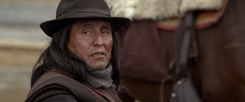 Movie still from “Blackthorn” (2011), directed by Mateo Gil – An older man with long black hair wearing a hat; Close Up shot, Over the shoulder angle