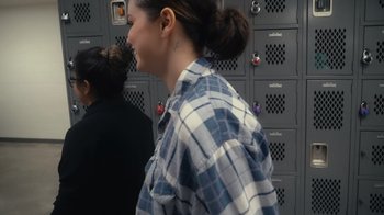 Movie still from “Selena Gomez: My Mind & Me” (2022), directed by Alek Keshishian – A woman in a plaid shirt standing in front of lockers; Close Up shot, Over the shoulder angle