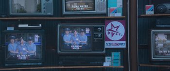 Movie still from “Seoul Vibe” (2022), directed by Hyun-Sung Moon – An old television set with three people on it; Extreme Close Up shot, Over the shoulder angle