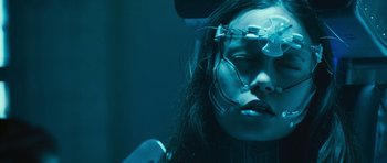 Movie still from “Serenity” (2005), directed by Joss Whedon – A woman wearing a pair of glasses with wires attached to her head; Close Up shot, Overhead angle