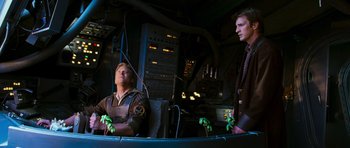 Movie still from “Serenity” (2005), directed by Joss Whedon – Two men are sitting next to each other in a room; Medium shot, Low angle