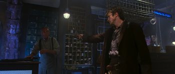 Movie still from “Serenity” (2005), directed by Joss Whedon – A man pointing at something while standing in a room; Medium shot, Low angle