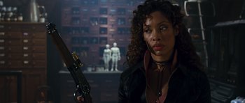 Movie still from “Serenity” (2005), directed by Joss Whedon – A woman holding a gun while standing in front of a wall; Close Up shot, Low angle