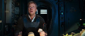 Movie still from “Serenity” (2005), directed by Joss Whedon – A man holding a remote control in a room; Close Up shot, Overhead angle