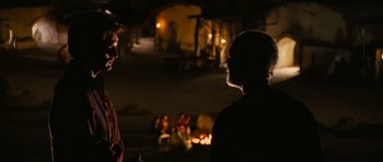 Movie still from “Serenity” (2005), directed by Joss Whedon – Two people standing in front of a fire pit; Medium shot, Over the shoulder angle