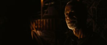 Movie still from “Serenity” (2005), directed by Joss Whedon – An old man with a beard is standing in the dark; Close Up shot, Over the shoulder angle