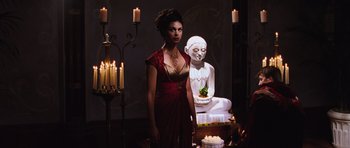 Movie still from “Serenity” (2005), directed by Joss Whedon – A woman standing in front of a buddha statue; Medium shot, High angle
