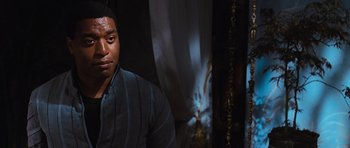 Movie still from “Serenity” (2005), directed by Joss Whedon – A man in a black and blue striped shirt; Close Up shot, Over the shoulder angle