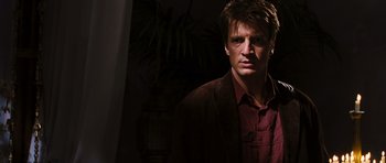 Movie still from “Serenity” (2005), directed by Joss Whedon – A man wearing a red shirt and a brown jacket; Close Up shot, Low angle
