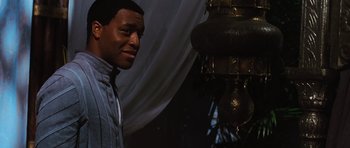 Movie still from “Serenity” (2005), directed by Joss Whedon – A man standing in front of an urn and a curtain; Medium shot, Over the shoulder angle