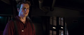 Movie still from “Serenity” (2005), directed by Joss Whedon – A man standing in a dark room with his hands in his pockets; Close Up shot, Low angle