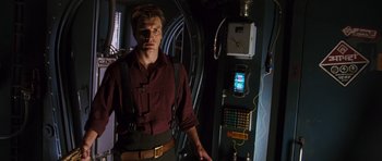Movie still from “Serenity” (2005), directed by Joss Whedon – A man standing next to a cell phone in a dark room; Medium shot, Low angle