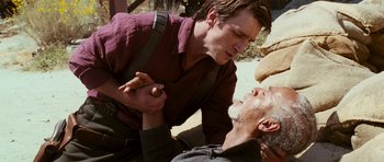 Movie still from “Serenity” (2005), directed by Joss Whedon – A man is helping another man who is lying on the ground; Close Up shot, Over the shoulder angle