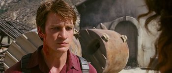 Movie still from “Serenity” (2005), directed by Joss Whedon – A man in a red shirt is standing in front of an object; Close Up shot, Over the shoulder angle